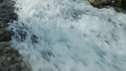 Beautiful water splashes in a slow motion. Small waterfall. Horizontal video.