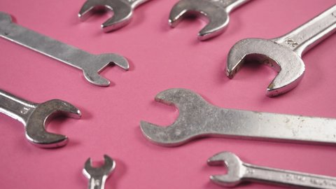 Close up of many spanner, wrenches of different sizes on pink background. Mechanical tools