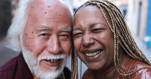 Multiracial senior couple smiling on camera outdoor 