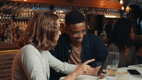 Diverse group of friends out for dinner laughing at cellular device 