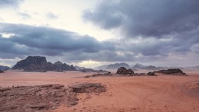 Red Mars like landscape in Wadi Rum desert, Jordan. Overcast morning - clouds moving over flat sand landscape with mountains in background, timelapse video
