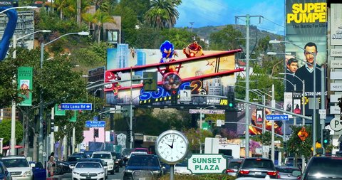 LOS ANGELES, CALIFORNIA, USA - MARCH 19, 2022: Luxury cars traffic on Sunset Strip on Sunset Boulevard at rush hour near giant movie billboards in Los Angeles, California, 4K