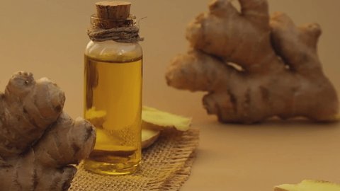 Glass bottle of essential ginger oil, ginger root on beige background. Healthy food eating concept. Zingiber officinale Essential oil. Natural cosmetics ingredients for skincare, body and hair care