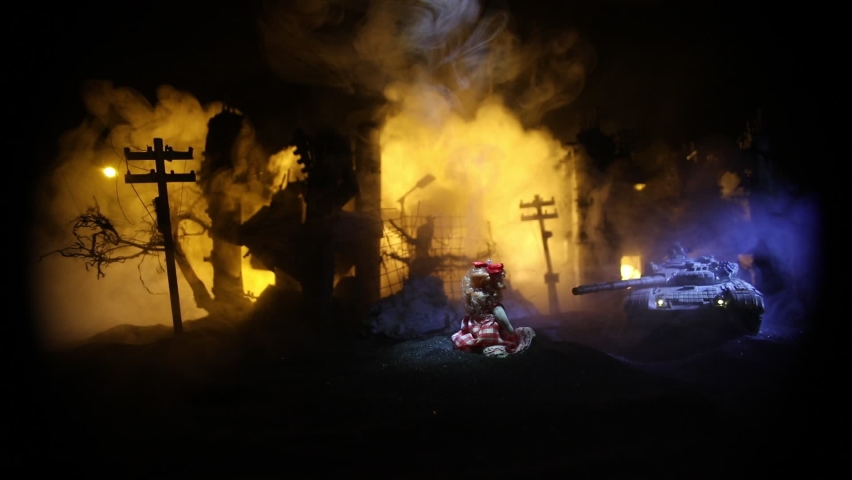 The death of children in the war. Russian war in Ukraine concept. Creative artwork of little doll lies on ground in burned out city. Selective focus
