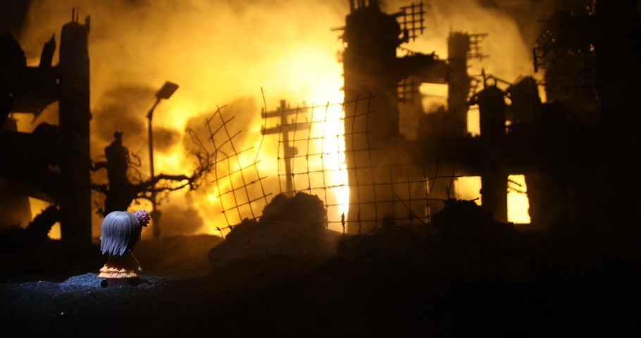 The death of children in the war. Russian war in Ukraine concept. Creative artwork of little doll lies on ground in burned out city. Selective focus
