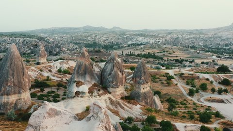 Stunning aerial panoramic shot, ancient houses carved inside beautiful tall rocks in Cappadocia mountain landscape.
