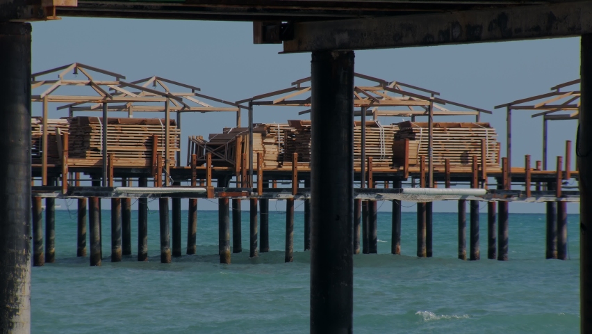 recreation area for tourists and holidaymakers on pier, sea waves are splashing in sunny day
