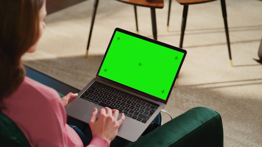 Young Adult Woman Working from Home Loft Apartment on Laptop Computer with Green Screen Mock Up Display. Creative Female Browsing the Web, Writing on Social Media. Close Up Over the Shoulder Footage. Royalty-Free Stock Footage #1088937115