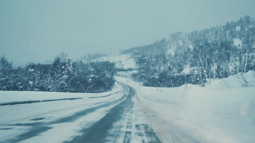 A car driving down the highway through snow blizzard. View through the car windshield. Royalty-Free Stock Footage #1088937937