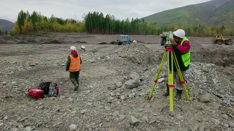 Mine surveyors are using the modern equipment to measure the gold quarry. Mine surveyors are analyzing the location using equipment at the gold quarry. Surveyors examine the gold mine using equipment