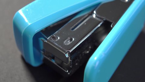 New blue office stapler on black paper. Macro. Rotation. School supplies