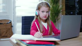 Focused child girl use headphones chatting studing at home during the coronavirus epidemic. Distance education concept. Online education. Teenage remote internet. Slow motion