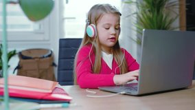 Serious child girl use headphones chatting studing at home during the coronavirus epidemic. Distance education concept. Online education. Teenage remote internet. Slow motion