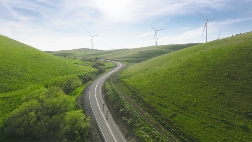 Cinematic solar power plant and Windmills aerial view on sunny summer day. Renewable energy, Green technology, climate change efforts concept footage. People on bicycles riding by countryside road USA | Shutterstock HD Video #1088938679