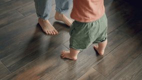 Little feet walking on floor, close-up. Baby learning to walk at home. Baby first steps. Smiling caring mother and cute little infant child girl cuddling in bedroom. Mum and child tender moments. - Powered by Shutterstock - Get 15% off with code: PIKWIZARD15