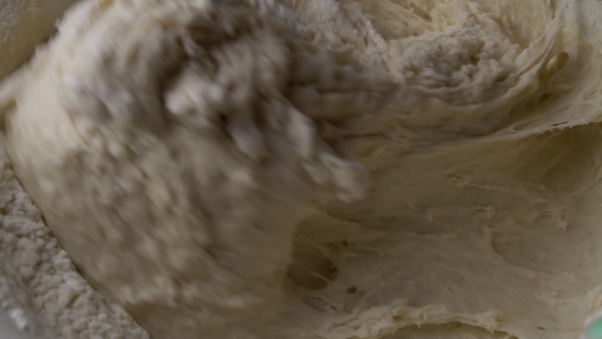 Mixing raw dough in slowmo close-up. Preparation of bakery products. Confectioner creates dough for baking. The process of mixing egg flour and yeast. Royalty-Free Stock Footage #1088940613