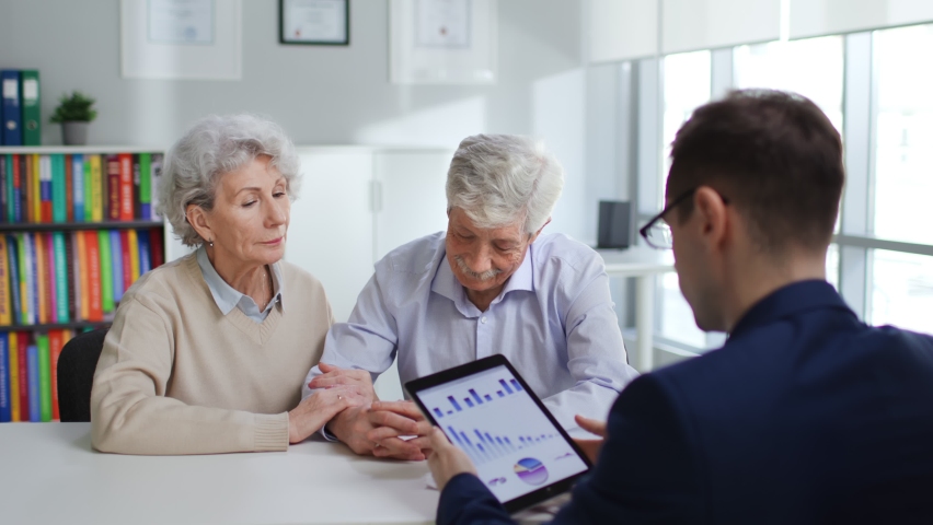 Broker consult senior couple about financial investment. Aged man and woman visit bank manager talking about loan | Shutterstock HD Video #1088941023