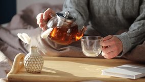 Woman pouring tea in mug from glass teapot. Cozy home hygge style interior. Tea ceremony at breakfast. - Powered by Shutterstock - Get 15% off with code: PIKWIZARD15