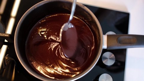 Melting and mixing a piece of butter in a saucepan on the gas stove, butter becoming liquid. Process melt chocolate