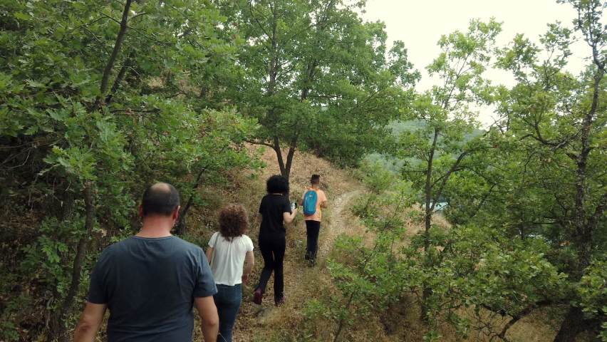 Family on a hiking adventure through the forest on the autumn mountain forest trail. Slow motion