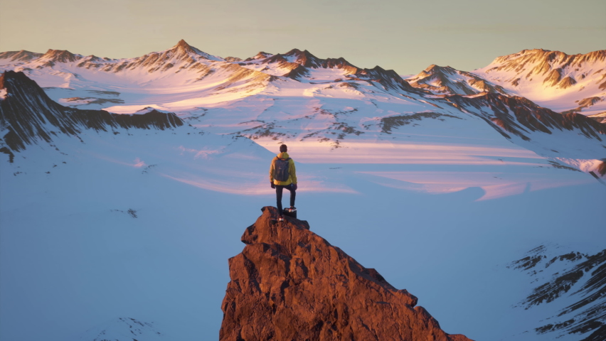 Aerial Around Young Hiker Man Standing on Mountain Peak Summit At Sunset Sunrise Expedition Challenge Drone Epic Adversity Conquering Fear Anxiety Concept CG | Shutterstock HD Video #1088945119