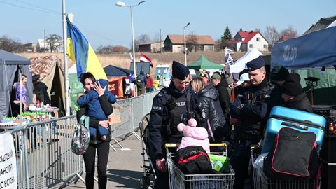 Medyka, Poland, March 2022: Refugees from Ukraine escaping from war. Ukrainian refugees on crossing the border to Poland. Ukrainians fleeing the war. Polish policeman trying to help refugees. 