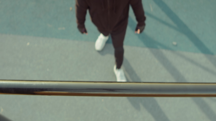 Top down shot of sporty man doing pull ups on horizontal bar while having outdoor workout on playground