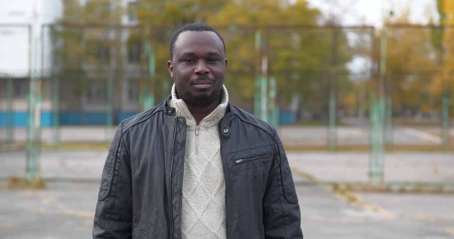 African american man from Nigeria stands on sport ground and look at the camera. Cinema 4K 60fps video