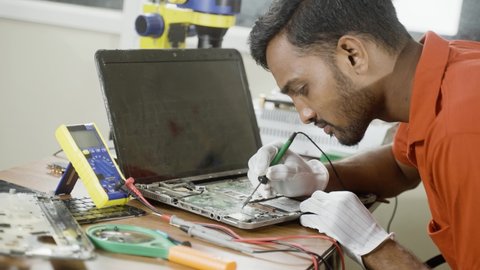 concentrated technician busy reparing laptop at workshop - concept of professional worker, skill jobs and repair service.