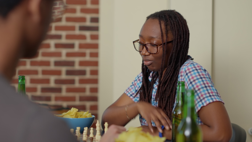 Positive woman having fun with chess board game at home, playing match with people for entertainment. Young adult relaxing with friends and competition match in living room, leisure activity. Royalty-Free Stock Footage #1088950005