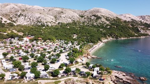 Stara Baska , Croatia - 08 30 2021: Tourists supping at the coast of Krk Island, Croatia - Aerial Drone View of Adriatic Sea, Boats, Beach, Mountains and Campsite