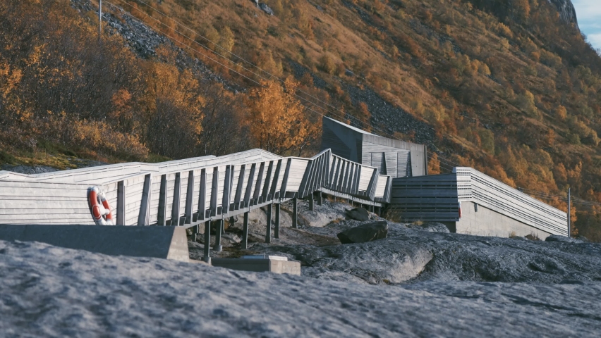 Tungenesset rest area on Sneja. A wooden footpath leads out over the rocks to the coast. Autumn forest on the mountain slopes.Slow-motion, pan right.