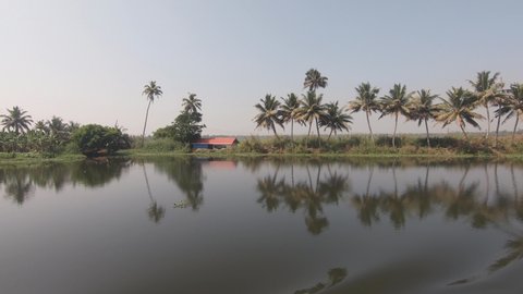 Tropical landscape, peaceful river surface, vessel navigate along Kerala backwaters, India