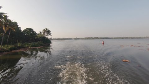 Tropical river shore in Kerala, vessel sailing along water plants, Alappuzha, India