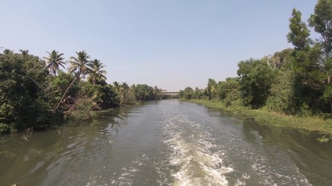 Boat view navigate along traditional waterway with lush vegetation in Alappuzha district, Kerala. India