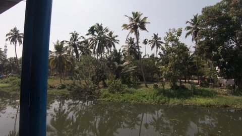 Tropical vegetation on Alappuzha traditional houseboat moored on shore, view from boat. India
