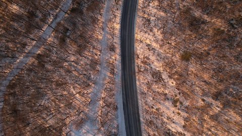 Aerial drone footage of a Beautiful Road through a snowy winter forest in the Appalachian mountains during winter in New York's Hudson Valley in the Catskill Mountains sub-range