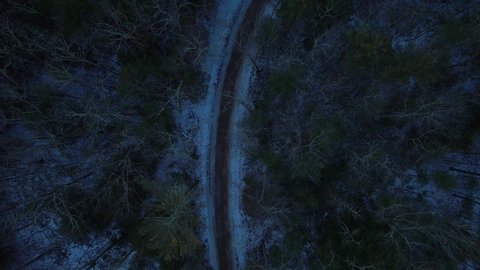 Smooth nighttime drone footage of a beautiful road through a snowy winter forest in the Appalachian mountains during winter in New York's Hudson Valley in the Catskill Mountains sub-range