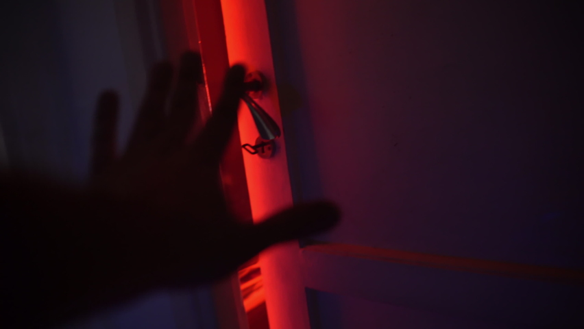 Horror scene with hand of unrecognisable person opening slowly door into the room with bright lighting, man entering into dark room for holding crime. High quality 4k footage