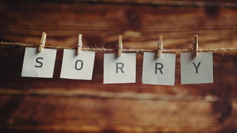 The word sorry. Letters on cards on wooden background. Apology or remorse and asking forgiveness. Concept of lettering and text or phrase.