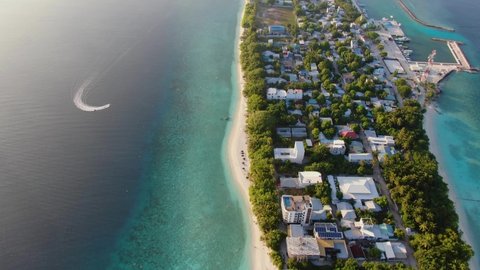 Ukulhas Maldive island sunset aerial view. Flying under paradise atoll with coral reef, sandy bay and palms