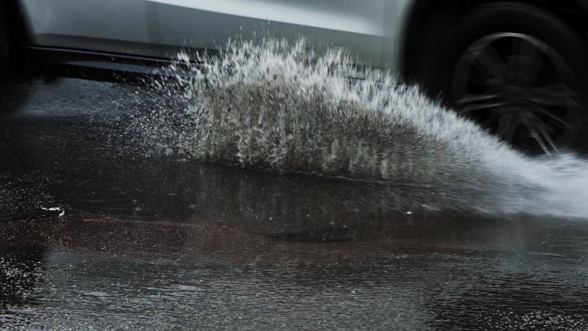 car drives into a puddle of water splashing around. slow motion. the rain floods the streets of the city. raindrops fall on asphalt, stormwind climate problems global warming Royalty-Free Stock Footage #1088959979