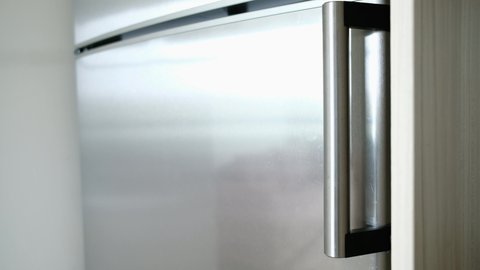 Close Up Video how hand opens and closes refrigerator metallic gray door