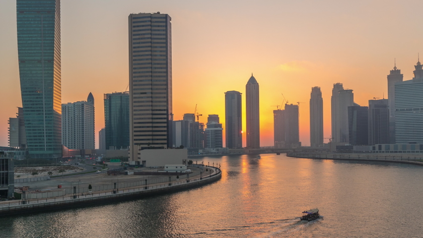 Modern city architecture in Business bay district at sunset. Panoramic aerial view of Dubai's skyscrapers reflected in water day to night transition timelapse Royalty-Free Stock Footage #1088964383