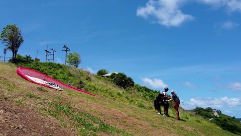 Phuket, Thailand, 25, March, 2022:
The pilot and paraglide instructor prepare the passenger for the flight, the paraglide passenger puts on the flight gear