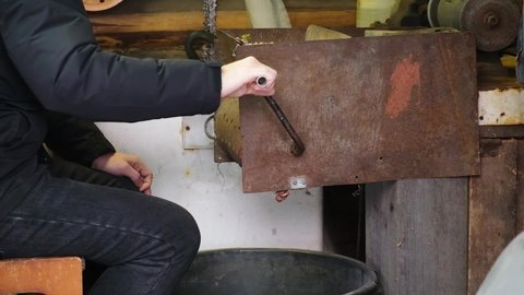 A man turns a homemade device for extracting cedar nuts from Siberian pine cones.