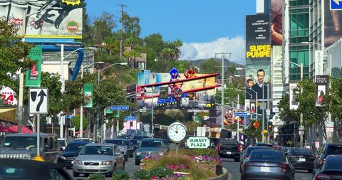 LOS ANGELES, CALIFORNIA, USA - MARCH 19, 2022: Luxury cars traffic on Sunset Strip on Sunset Boulevard at rush hour near giant movie billboard in Los Angeles, California, 4K