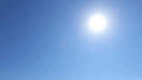 Bright sun light ray n sunbeam lens flare on beautiful sunny clear blue sky background with cloudless space in tropical summer or spring sunlight n sunray at daylight, 4k cinemagraph b-roll TimeLapse