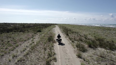 Video with Drone "follow me" to a motorcyclist driving along the beach. Beach in albania coast, durres, spille. High displacement motorcycle of well-known brand. Lonely traveling nomad biker.