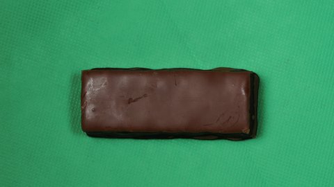 Stop motion of eating chocolate bar bite by bite, green background.